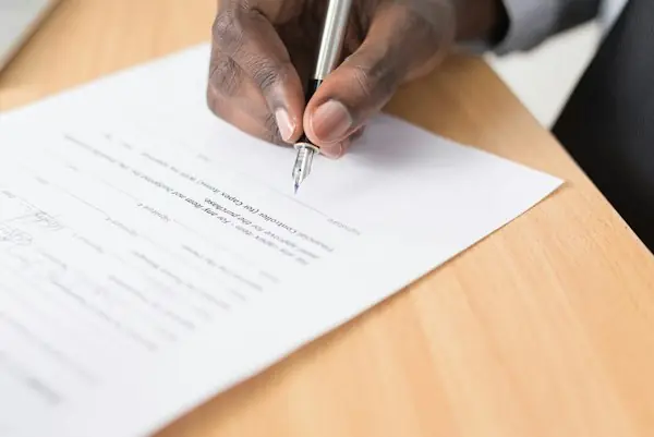 Hand signing a paper document with a pen, representing the patient signature on an Advance Beneficiary Notice of Noncoverage
