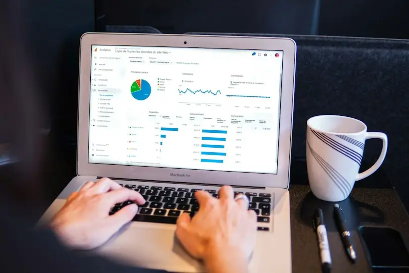 Hands typing on a laptop beside a coffee mug with a coordination of benefits dashboard on screen, representing Medicare Secondary Payer verification