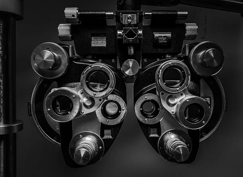 Optometrist adjusting a phoropter during an eye exam, representing the split between medical and routine optometry billing