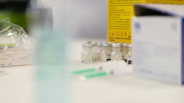 Small glass vials of medication lined up on a clinic counter beside packaging, representing single-dose Part B drug billing