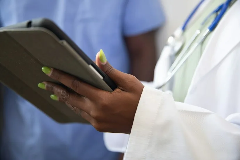Physician reviewing AI-generated clinical documentation on a tablet, representing AI medical scribe billing compliance