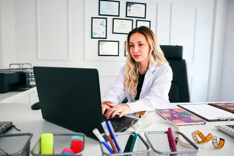 Physician reviewing a patient chart on a laptop, representing HCC risk adjustment documentation review