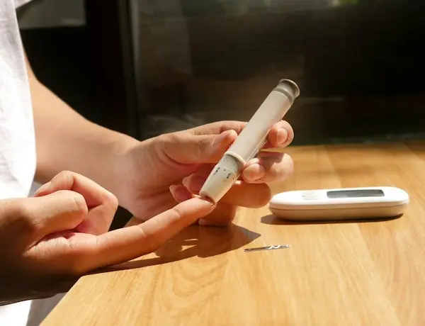 Patient performing a self-administered blood glucose test as part of diabetes self-management education