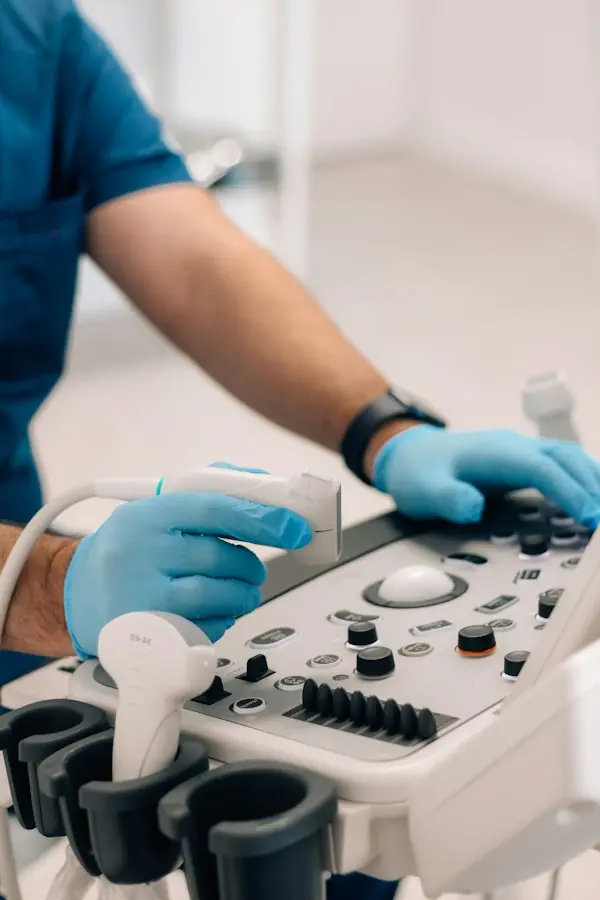 Clinician operating an ultrasound machine control panel during a maternal-fetal medicine consultation